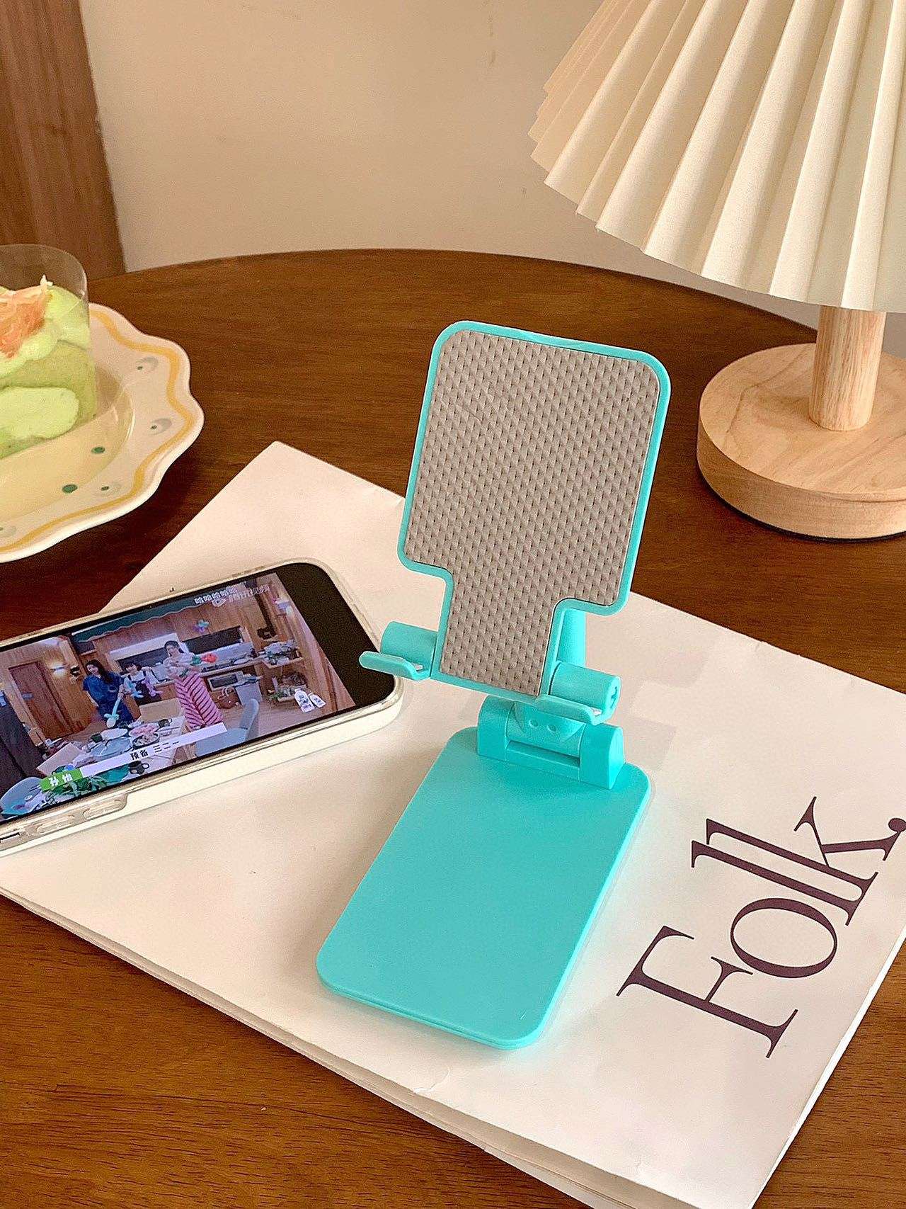 Folding mobile phone stand, teal base with textured back panel and angled support