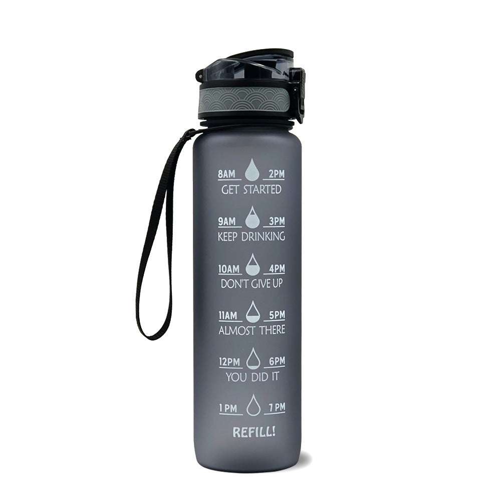 Motivational water bottle with time markers, dark gray body, flip lid, and carry loop