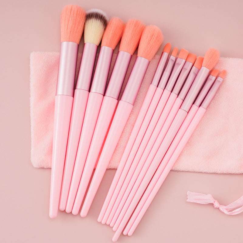 Makeup brush set with peach and pink bristles and pink-white handles, on cloth