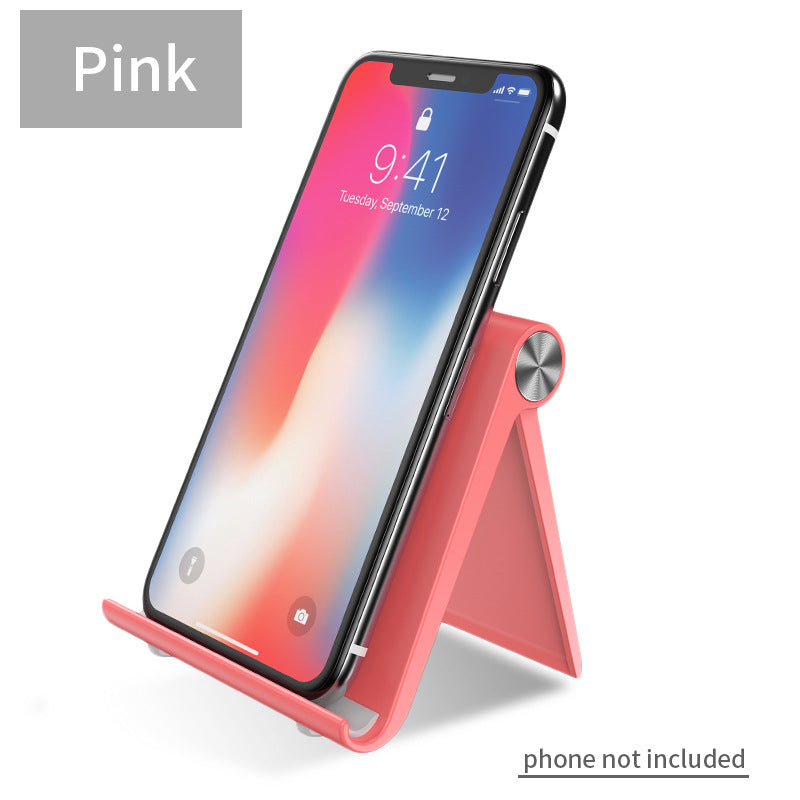 Pink desktop phone stand with angled legs and circular knob, holding a smartphone