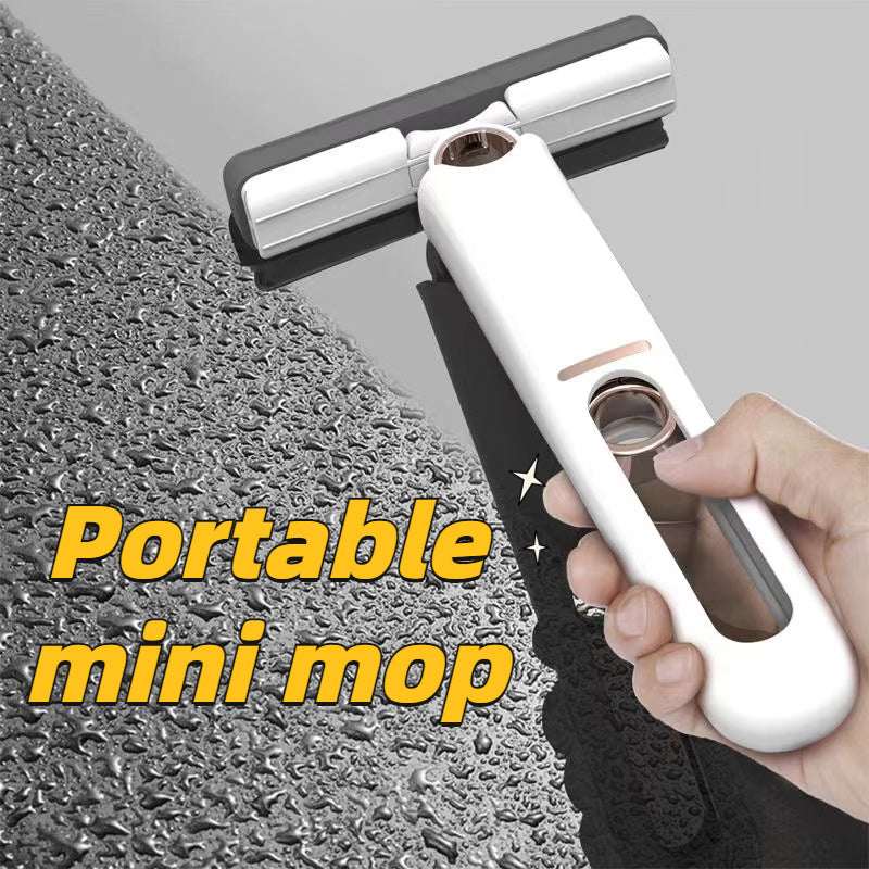 White portable self-squeeze mini mop with rectangular head, held by hand over scrubbing surface