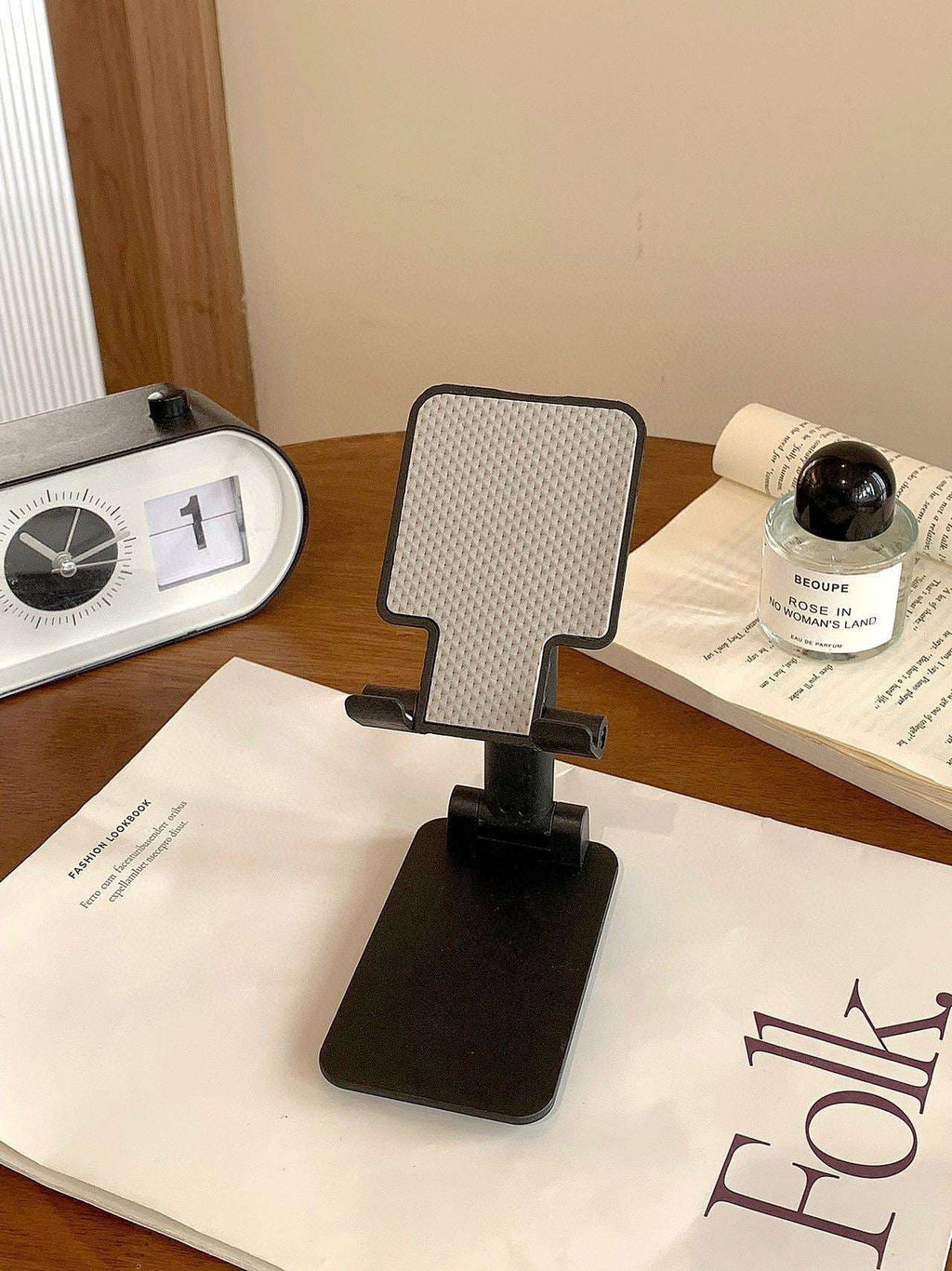 Folding mobile phone stand, dark/black base with textured back panel and angled grip