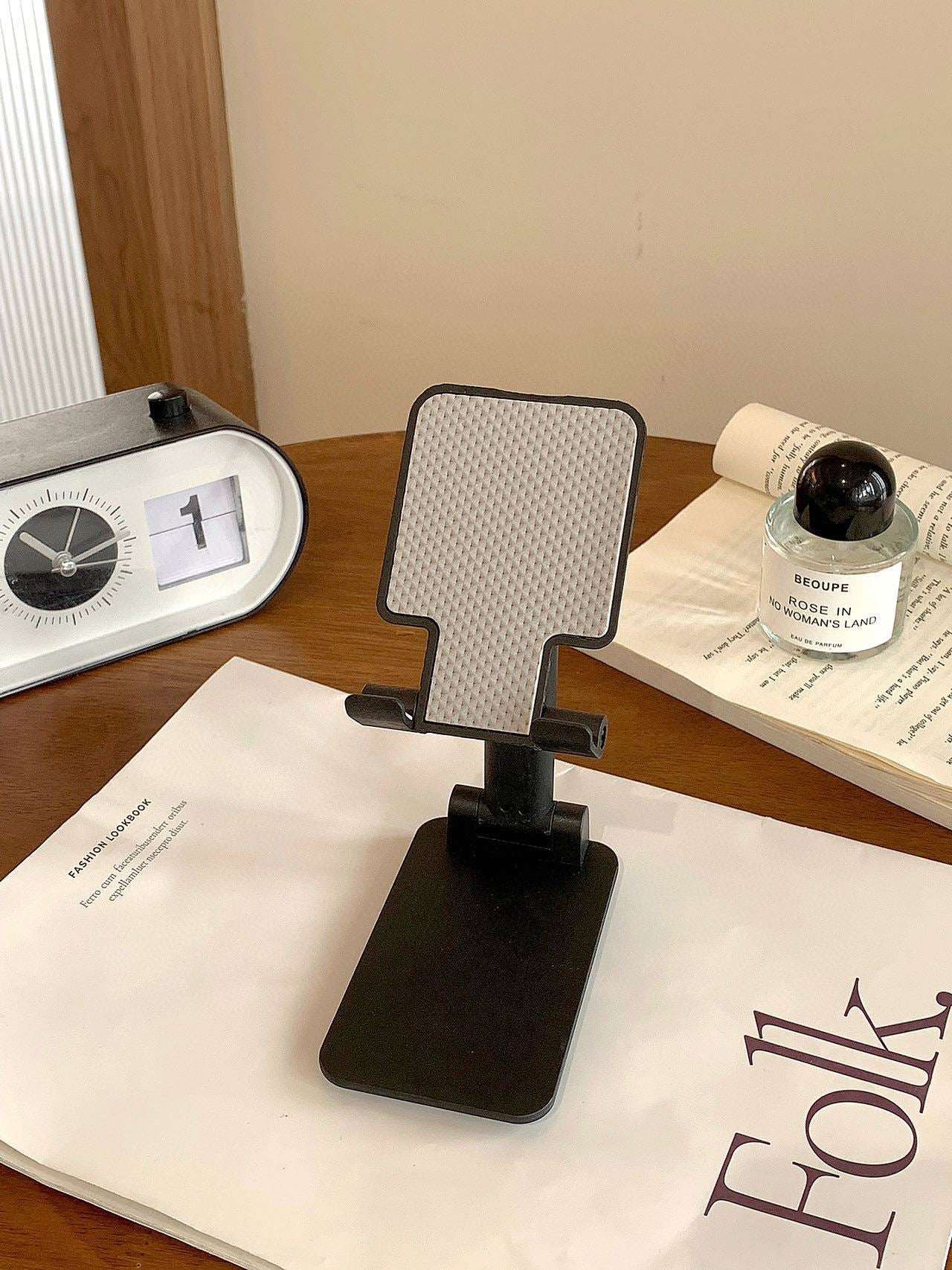 Folding mobile phone stand, dark/black base with textured back panel and angled grip