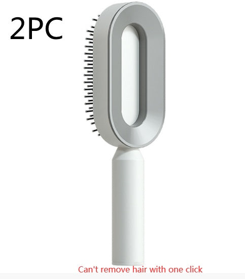 Self-cleaning hair brush standing upright with grey bristle head and white handle